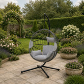 Luxury light grey hanging egg chair with plush cushions and woven rattan-effect design in a stylish modern garden patio.