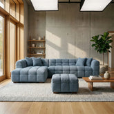 Luxury bouclé corner sofa with chaise and matching footstool in iron grey, featuring a modern curved design for contemporary UK living rooms.
