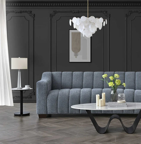 Luxury 3 seater bouclé sofa with deep channel tufting, curved arms and premium textured upholstery in a modern UK living room.