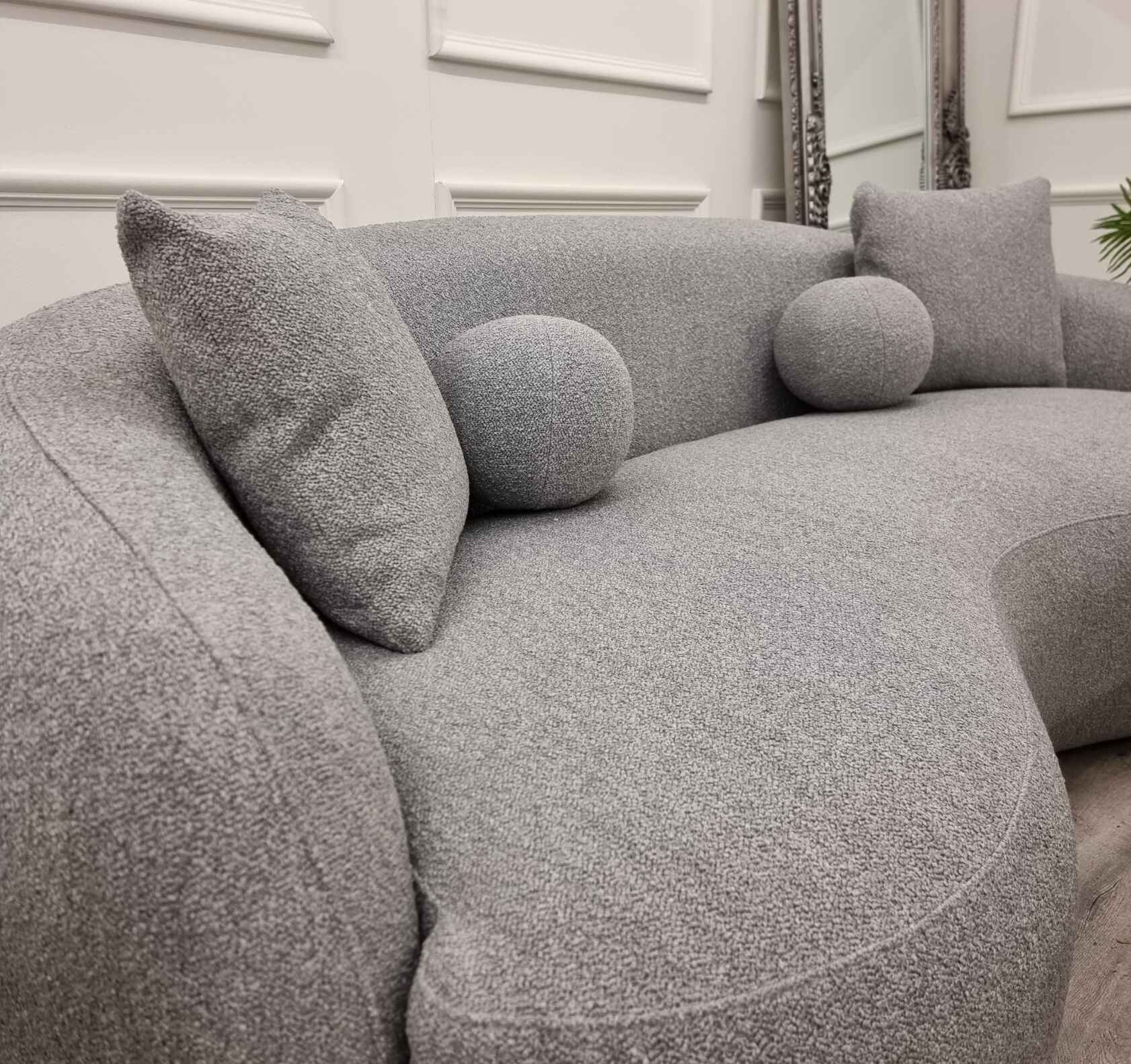Luxury grey Wave bouclé sofa with a sculptural curved silhouette, premium textured upholstery, deep foam cushions, and modern designer styling.