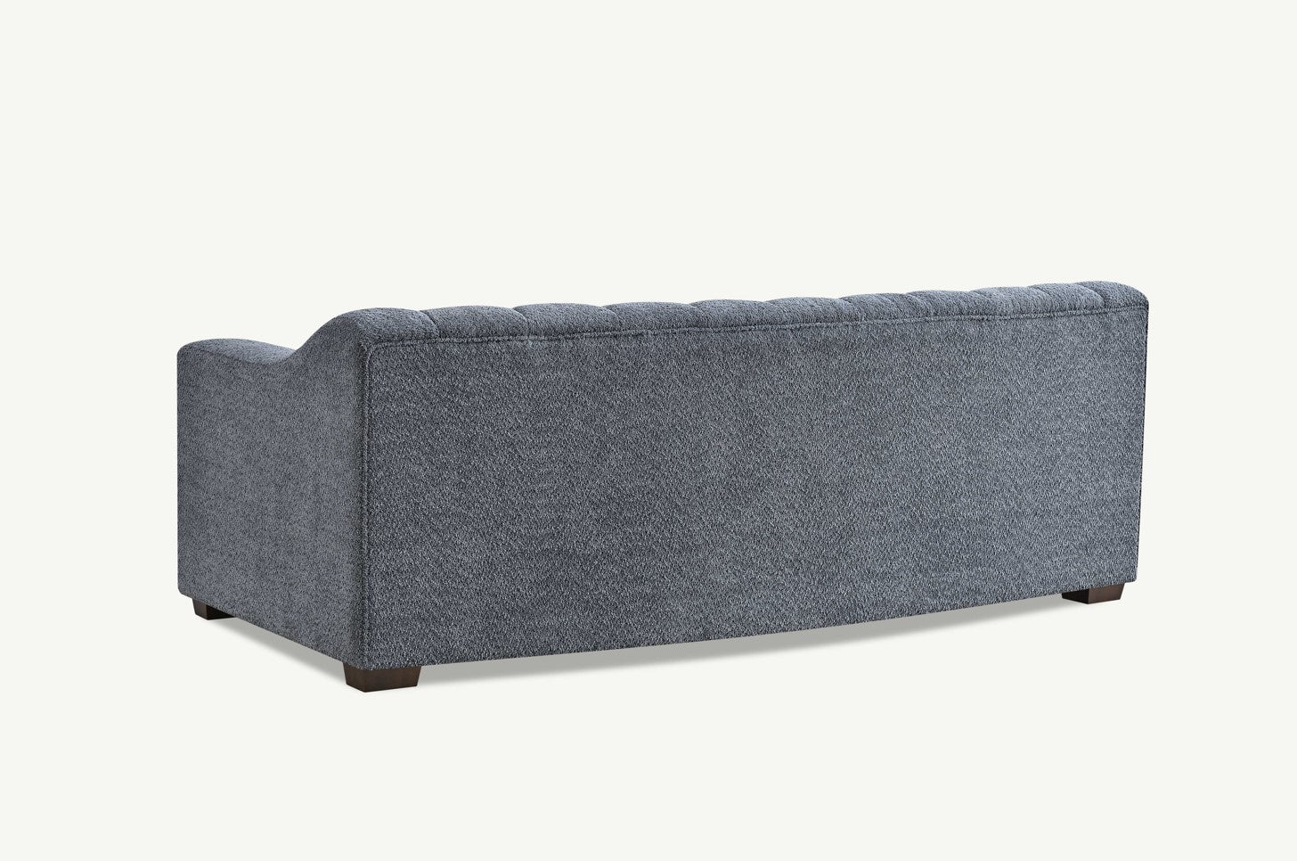 Luxury 3 seater sofa with deep channel tufting, curved arms and premium textured upholstery in a modern UK living room.