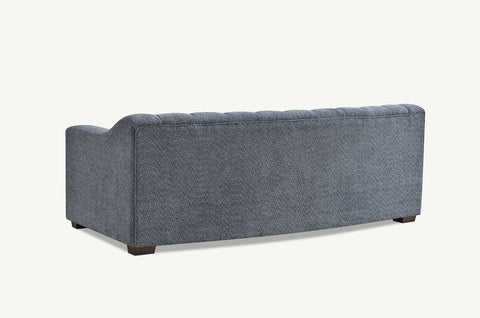 Luxury 3 seater sofa with deep channel tufting, curved arms and premium textured upholstery in a modern UK living room.