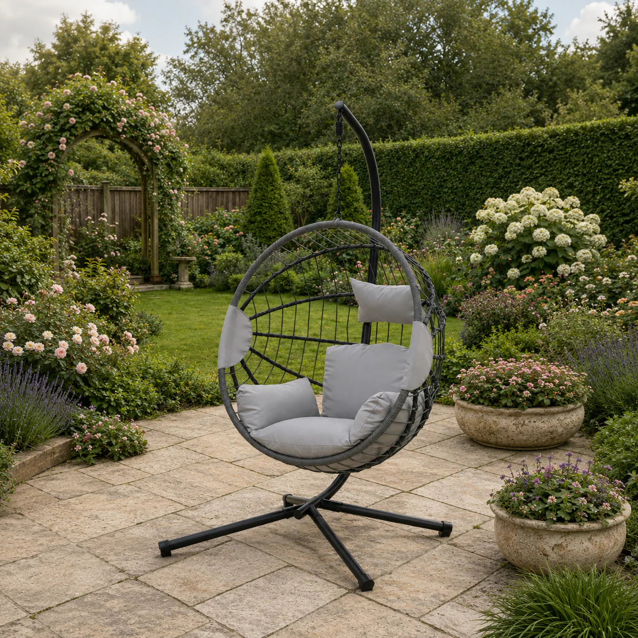 Luxury light grey hanging egg chair with plush cushions and woven rattan-effect design in a stylish modern garden patio.