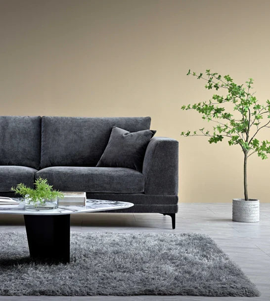 Luxury steel grey velvet sofa with a mid-century modern design, wooden plinth base, deep cushions, and elegant clean lines for contemporary UK living rooms.