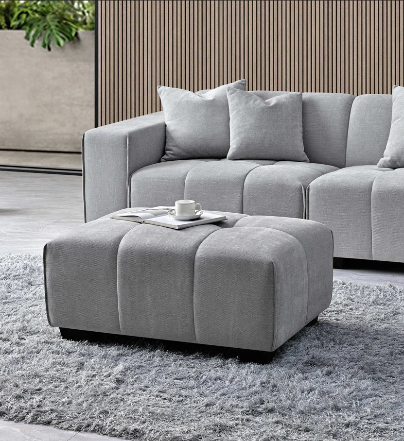 cloudy grey bouclé right-hand corner sofa with modular L-shaped design, block-stitched cushions, and five matching scatter cushions in a contemporary living room.
