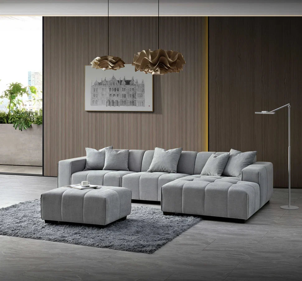 Luxury cloudy grey bouclé right-hand corner sofa with modular L-shaped design, block-stitched cushions, and five matching scatter cushions in a contemporary living room.