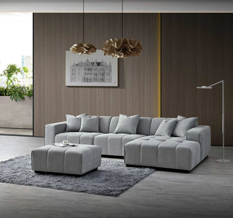 Luxury cloudy grey bouclé right-hand corner sofa with modular L-shaped design, block-stitched cushions, and five matching scatter cushions in a contemporary living room.