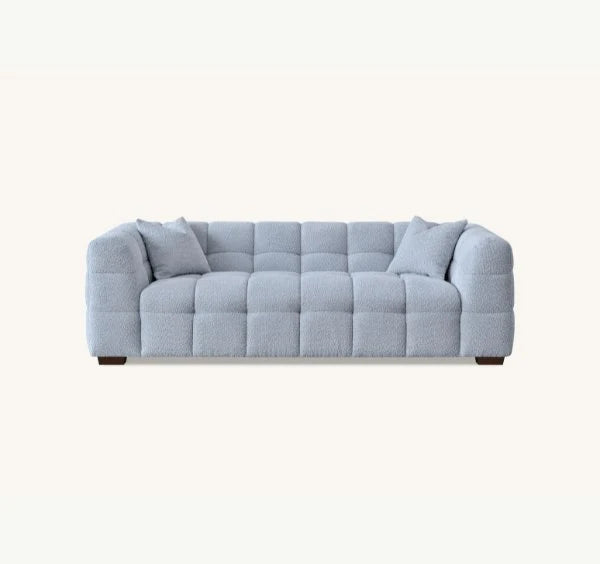 Pearl Bouclé sofa featuring sculptural curved arms, deep channel stitching, premium textured upholstery, and contemporary designer styling for modern UK homes.
