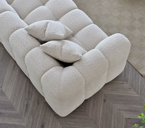 Tribeca oatmeal bouclé sofa with sculptural curved silhouette, deep channel stitching, premium textured upholstery, and contemporary designer styling for modern UK homes.